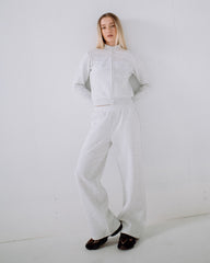 Person wearing a light gray jumpsuit against a white background
