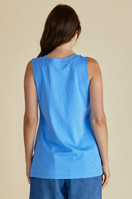 Woman wearing a blue sleeveless top against a beige background