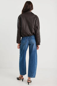 Person wearing a black leather jacket and blue jeans on a white background