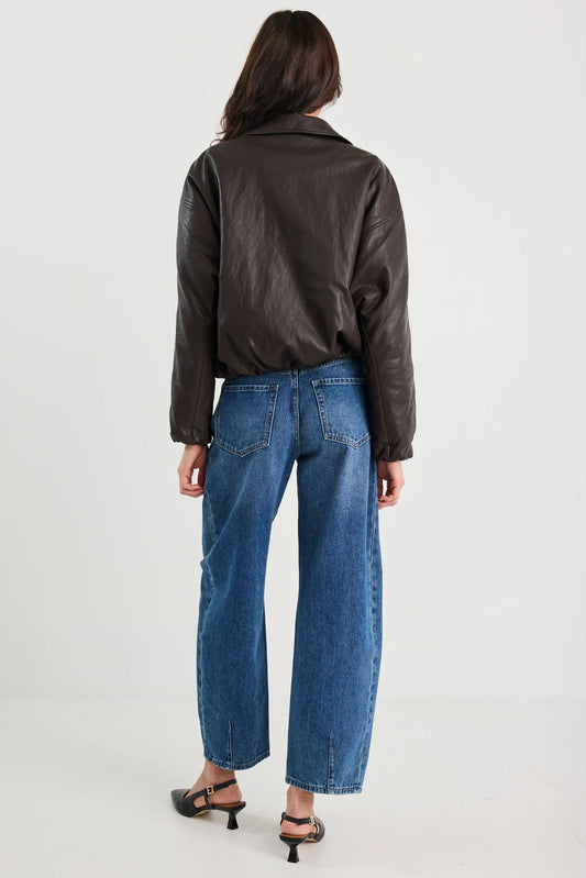 Person wearing a black leather jacket and blue jeans on a white background