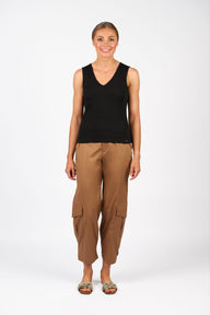 Woman wearing a black sleeveless top and brown cargo pants on a white background