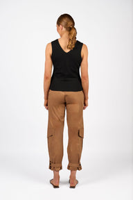 Person wearing a black sleeveless top and brown cargo pants on a white background
