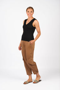 Woman wearing a black sleeveless top and brown pants on a white background