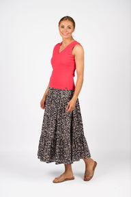 Woman wearing a red sleeveless top and patterned skirt on a white background