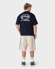 Person wearing a navy blue t-shirt with a logo on the back, standing against a white background