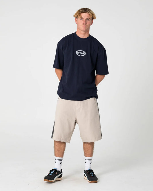 Person wearing a navy blue t-shirt with a logo and beige shorts on a white background