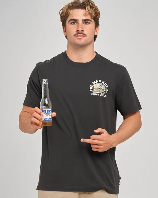 Man wearing a Washed Black Tee holding a bottle of beer with a grey background