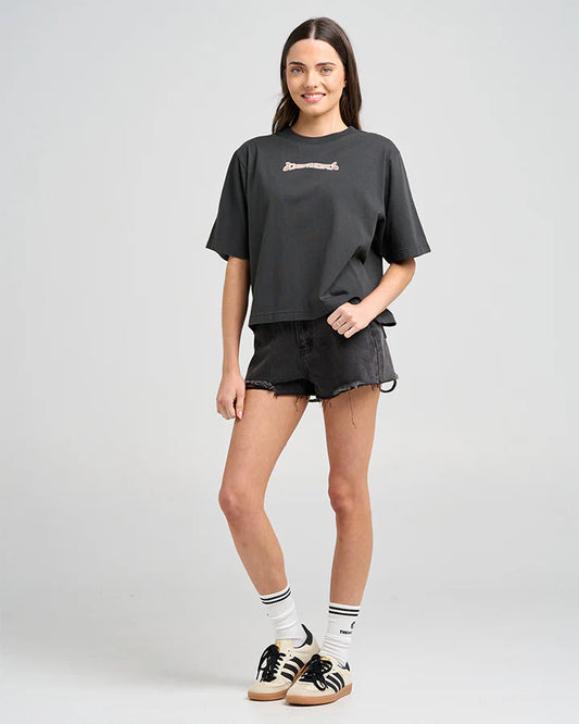Woman wearing a black oversized t-shirt, black shorts, and Adidas shoes on a white background