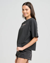 Woman wearing a black oversized t-shirt and denim shorts on a light gray background