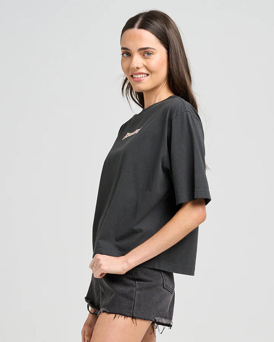 Woman wearing a black oversized t-shirt and denim shorts on a light gray background