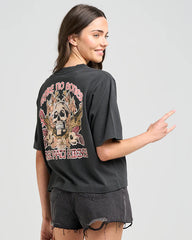 Woman wearing a black t-shirt with a graphic design on the back, pointing to the design.