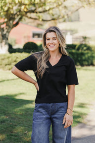 Lady wearing a black tee with blue jeans in a garden with a tree