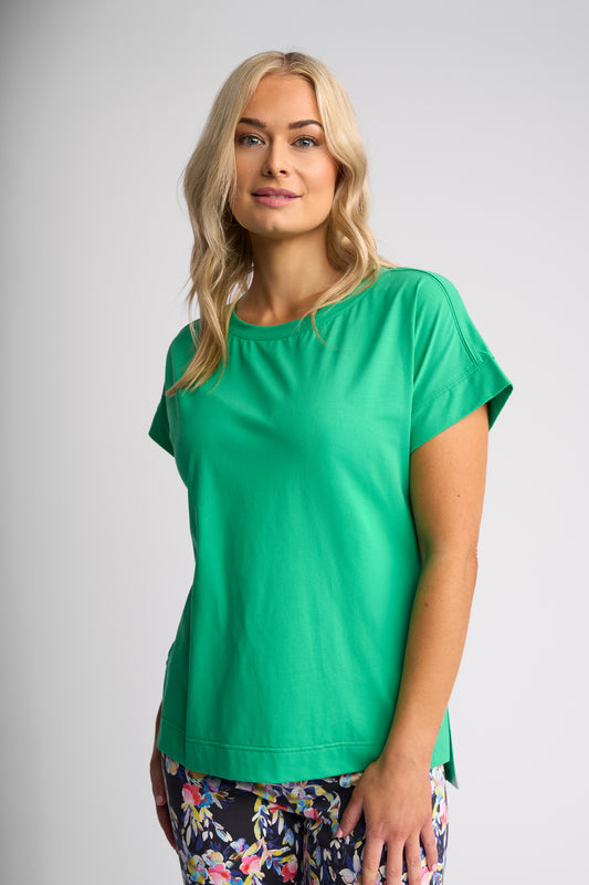 A woman modeling a bright green short-sleeve top against a light gray studio background.