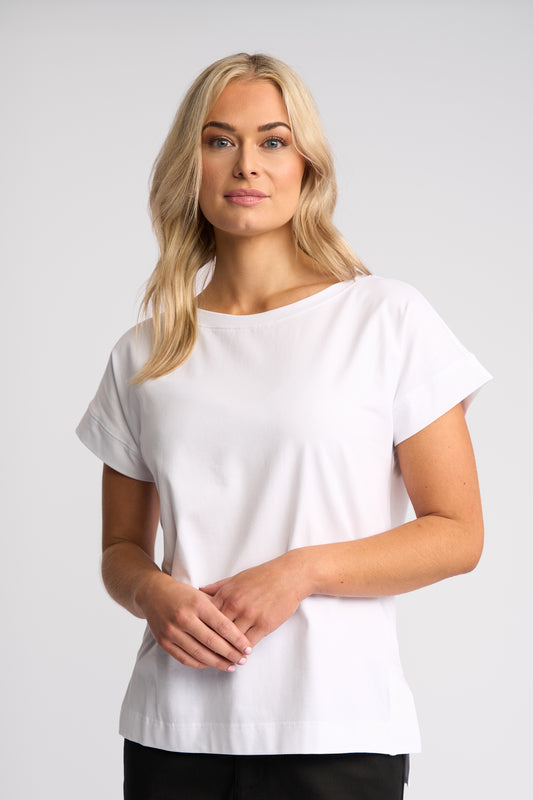 A blonde woman wearing a white short-sleeve crewneck t-shirt, standing against a light gray studio background.