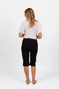 Woman wearing Vassalli Below Knee Skinny Leg Elastic Waist Pant with white top and white background