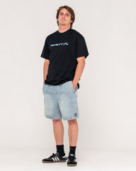 Person wearing a black t-shirt with a logo and light blue shorts on a white background