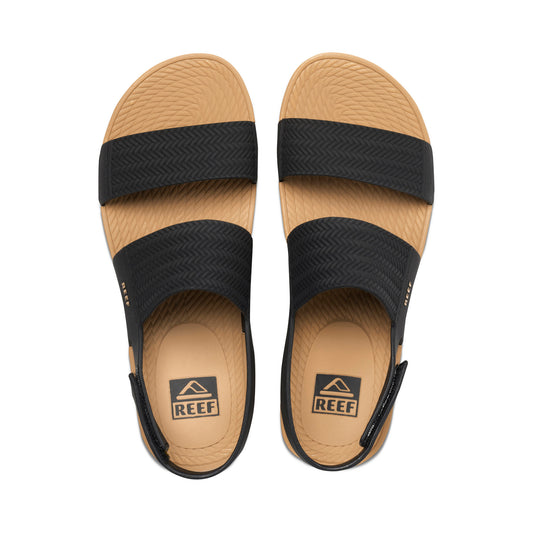 Pair of Reef sandals with black straps on a white background