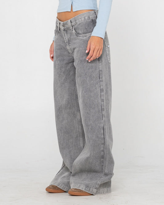 Person wearing gray wide-leg jeans and a light blue top on a white background