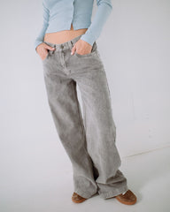 Person wearing light blue cropped top and gray wide-leg jeans on a white background