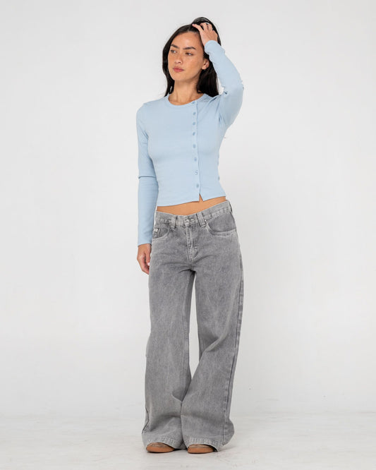 Woman wearing a light blue cardigan and gray wide-leg jeans on a white background