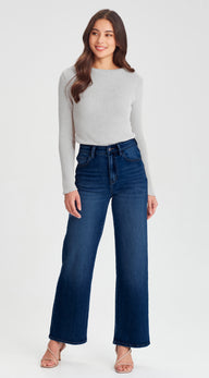 Woman wearing a gray sweater and blue jeans on a white background