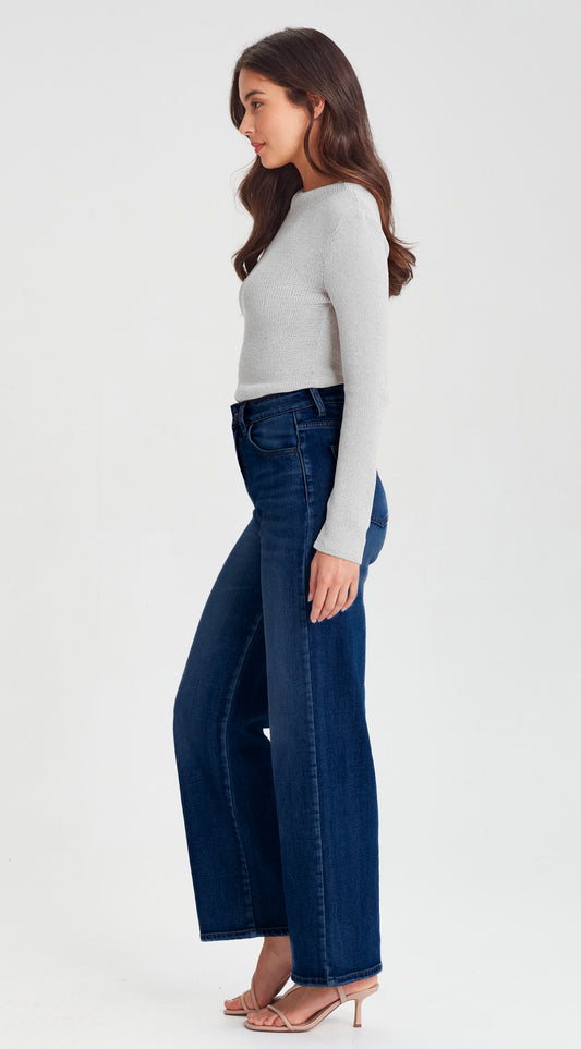 Woman wearing a white long-sleeve top and dark blue jeans on a white background