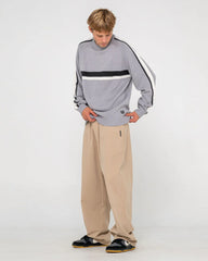 Person wearing a gray sweater with black and white stripes and beige pants on a white background