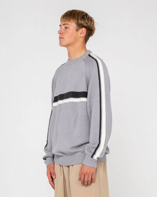 Person wearing a gray sweater with black and white stripes on a plain background