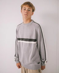 Person wearing a gray sweater with black and white stripes on a plain background