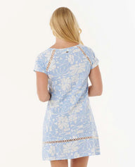 Woman wearing a light blue floral dress with lace trim on a white background