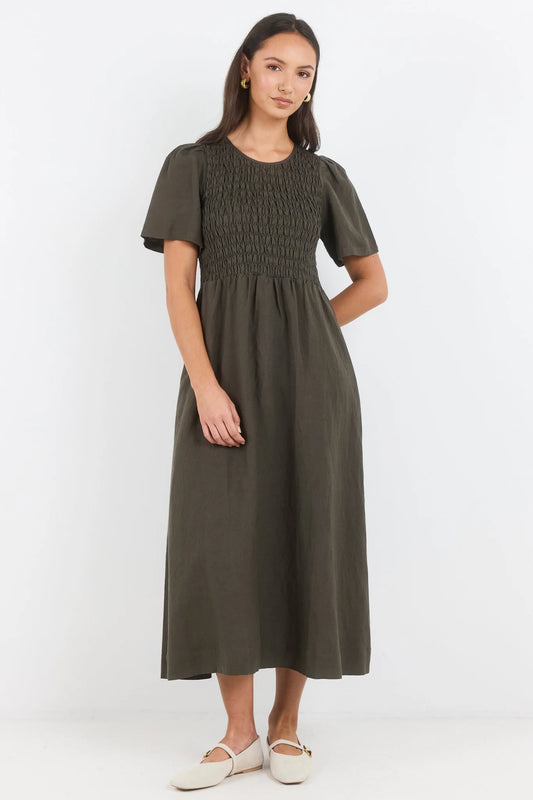 Woman wearing a green dress with smocked bodice and plain skirt on a white background