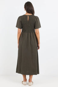 Woman wearing a green dress with smocked bodice on a white background
