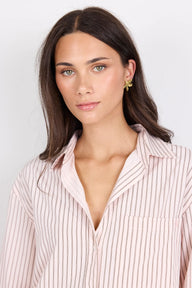 Woman wearing a light pink striped shirt against a plain background