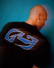 Person wearing a black t-shirt with a blue logo on the back against a blue background