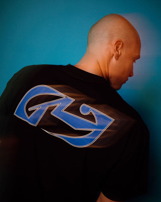 Person wearing a black t-shirt with a blue logo on the back against a blue background