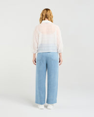 Woman wearing Zafina Heidi white blouse and light blue striped pants on a white background