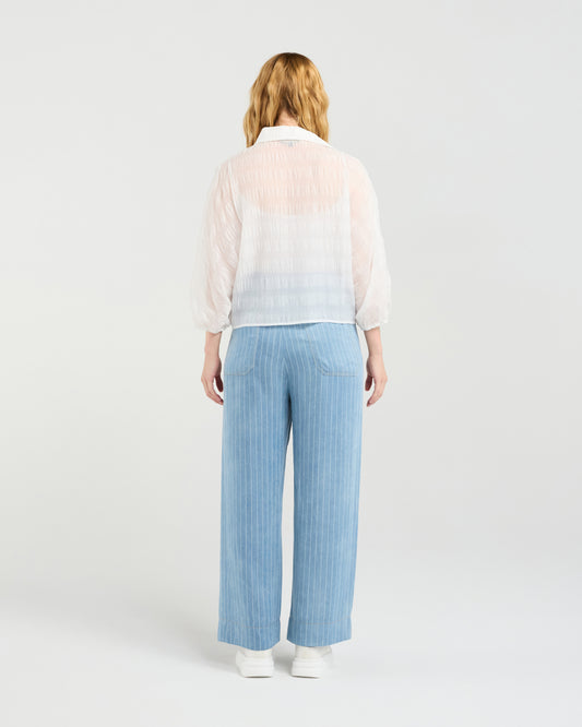 Woman wearing Zafina Heidi white blouse and light blue striped pants on a white background