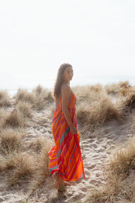 Woman in a colorful dress standing on a sandy path with grasses around