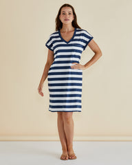 Woman wearing a blue and white striped dress against a beige background