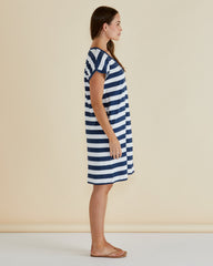 Woman wearing a blue and white striped dress against a beige background
