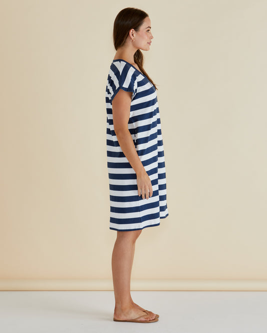 Woman wearing a blue and white striped dress against a beige background
