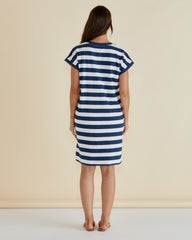 Woman wearing a blue and white striped dress against a beige background