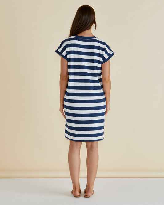 Woman wearing a blue and white striped dress against a beige background