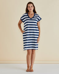 Woman wearing a blue and white striped dress against a beige background