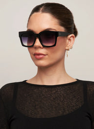 Woman wearing black sunglasses with a plain background