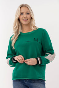 Woman wearing a green sweatshirt with a logo on a white background