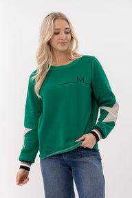 Woman wearing a green sweater with a logo on a white background