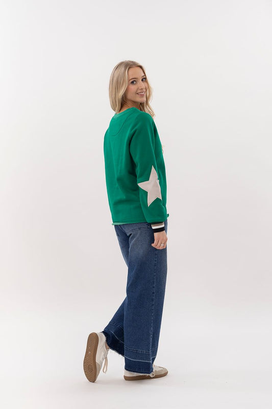 Woman wearing a green sweater with a white star design on a white background