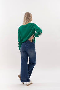 Person wearing a green sweater and blue jeans on a white background