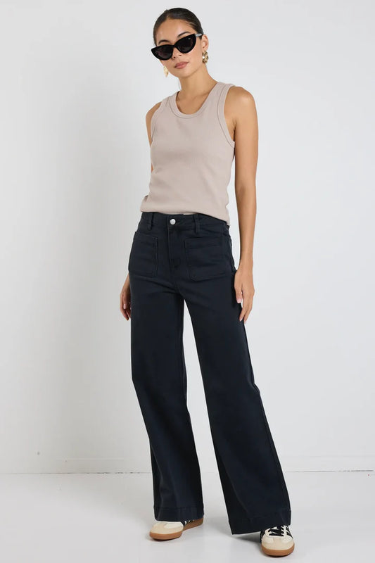 Woman wearing a beige sleeveless top and Amoung the Brave Zoey black wide-leg pants against a white background